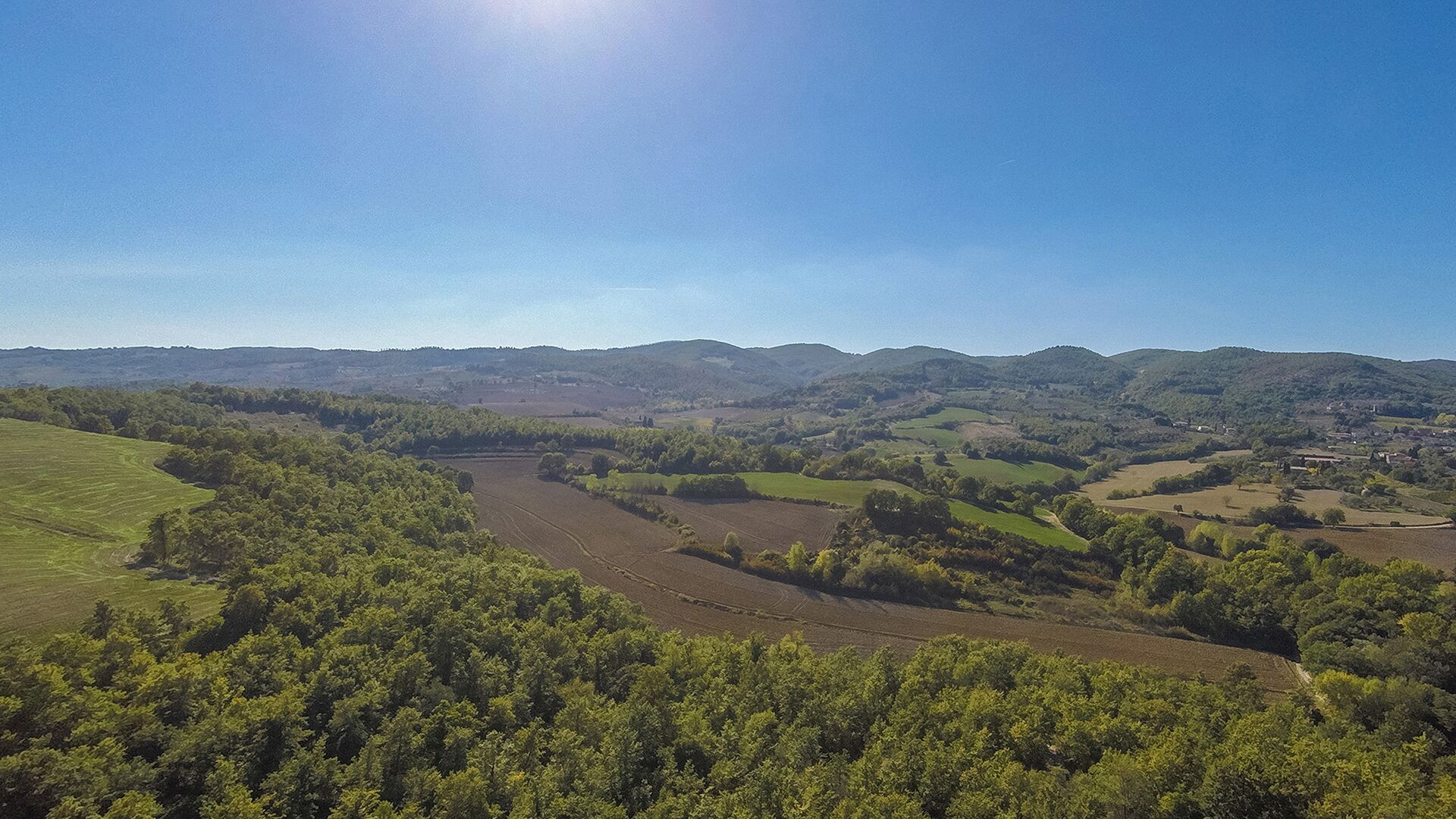 Un paysage rural caractérisé par des collines douces, des champs et une rivière.