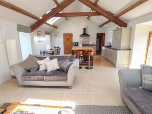 A spacious living area with a sofa, a dining table, and a kitchen in the background. - Wern Olau Cottage (Caernarfon)