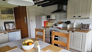 A compact kitchen with a dining area, featuring a microwave, stove, and toaster. - Nant-isa (Shrewsbury)