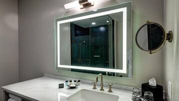 Un bagno moderno con uno specchio grande, un lavandino bianco e una cabina doccia in vetro.