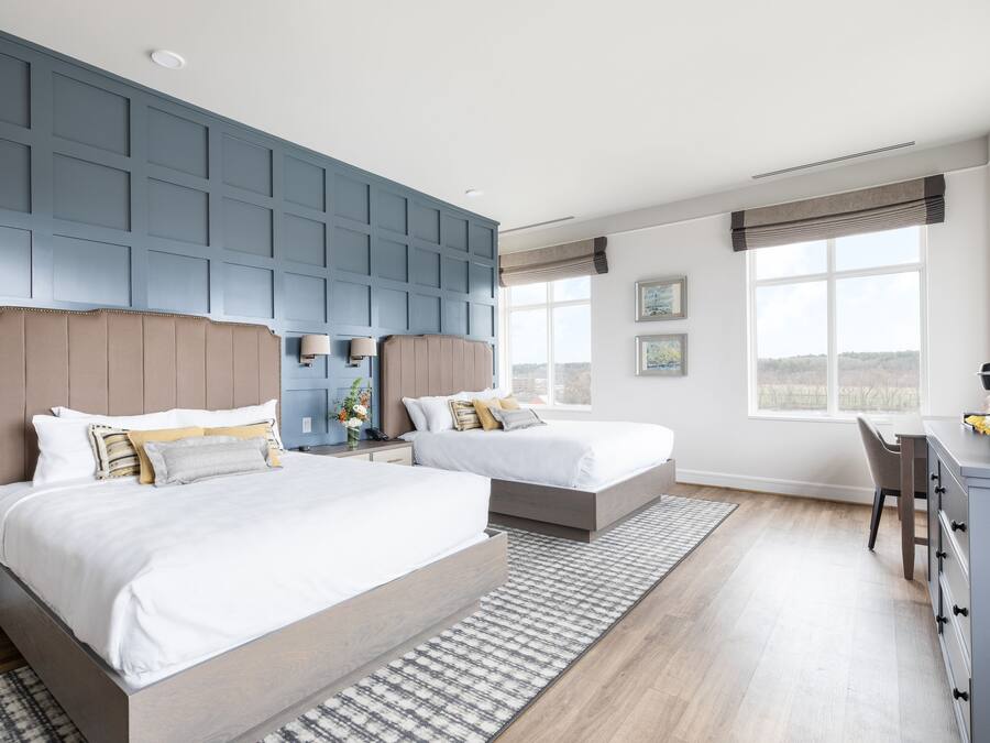 Une chambre d’hôtel moderne avec deux lits, un bureau et une vue sur l’extérieur.