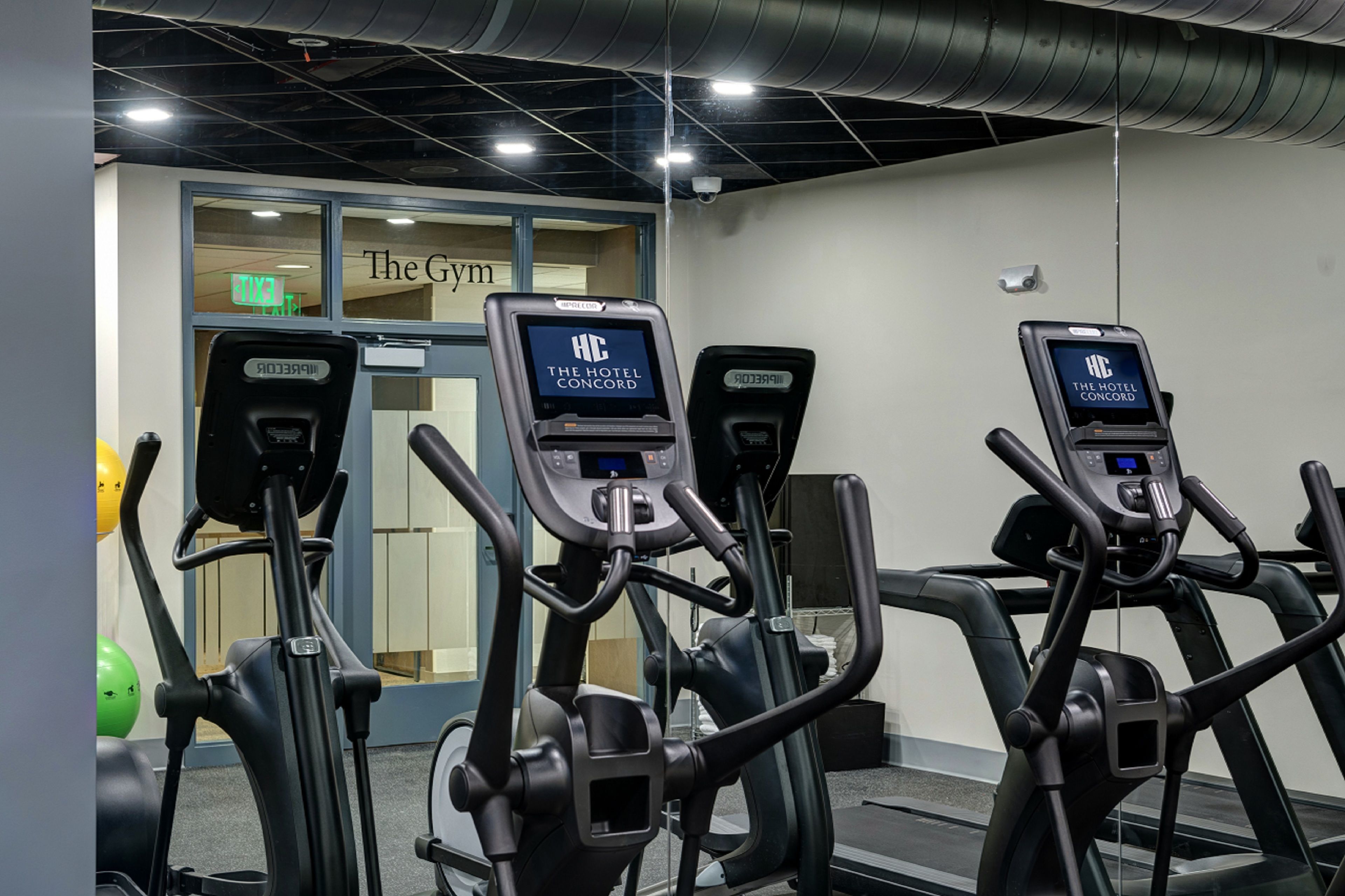 Tres bicicletas estáticas con pantallas digitales en un área de gimnasio de un hotel.
