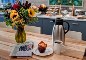 A breakfast setting with a newspaper, muffin, coffee cup, and a thermos on a wooden table. - The Hotel Concord (Concord)
