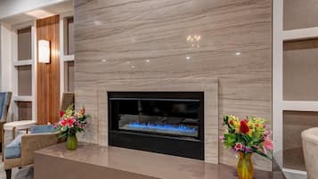 A modern living room with a fireplace, two vases of flowers, and contemporary furniture.