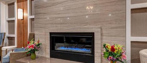 A modern living room with a fireplace, two vases of flowers, and contemporary furniture.