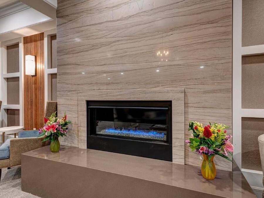 A modern living room with a fireplace, two vases of flowers, and contemporary furniture.