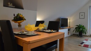 Un coin repas avec une table en bois, des chaises noires et un vase rempli de fleurs jaunes.