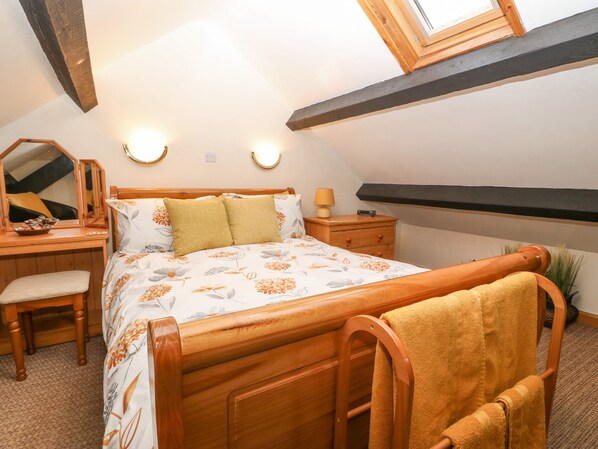 A bedroom with a wooden bed, a desk, a chair, and a nightstand. - Bwthyn Ael Y Bryn (Garndolbenmaen)