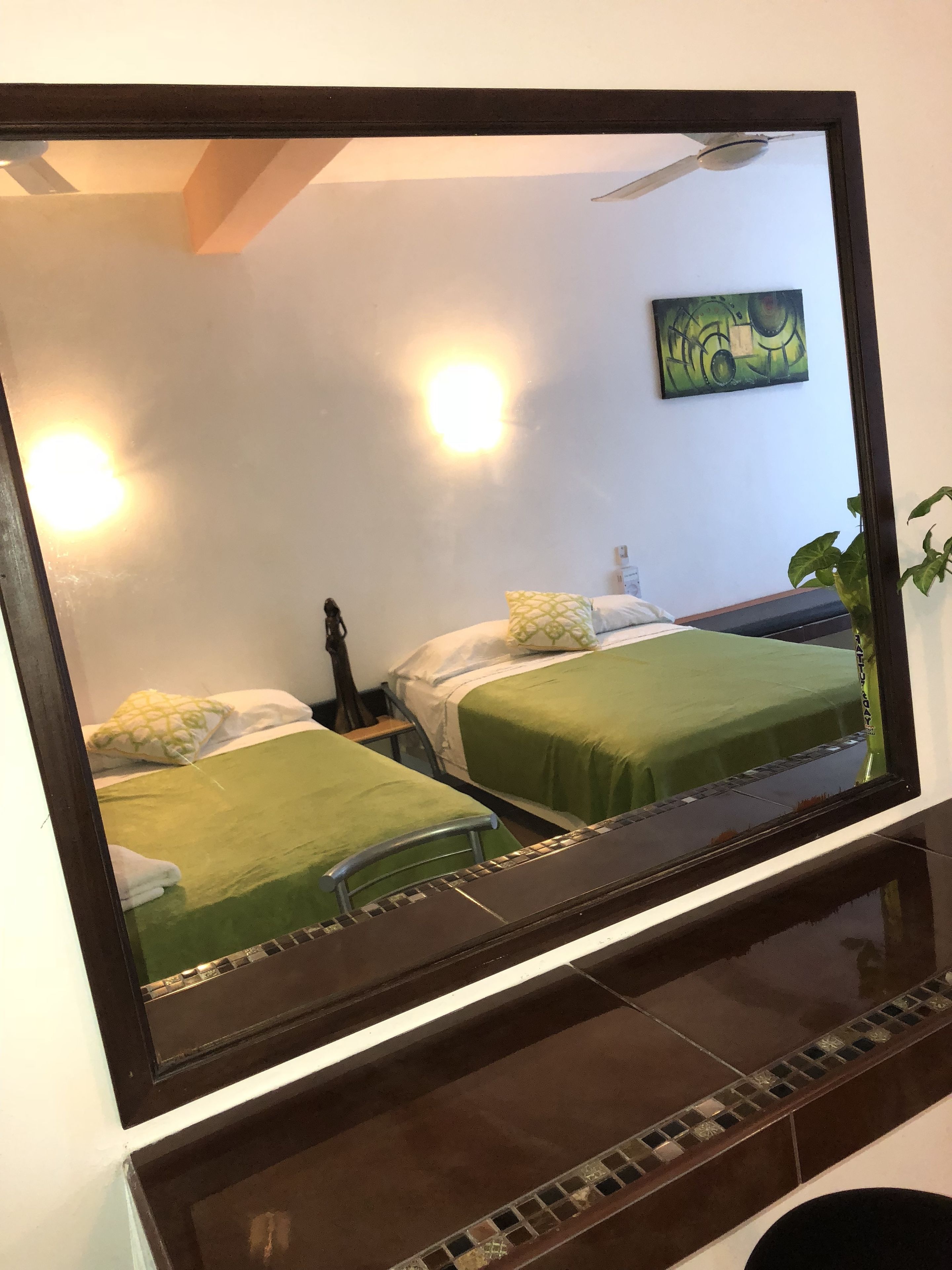 A bedroom with two beds, a nightstand, a lamp, and a painting on the wall.
