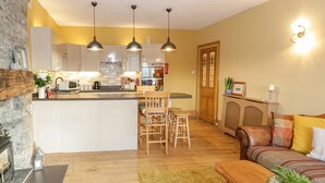 A modern kitchen with white cabinets, a central island, and pendant lighting. - Castle Apartment (Conwy)