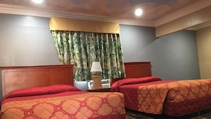 A hotel room with two beds, a nightstand, a lamp, and a window with curtains. - Budget Inn (Lawndale)