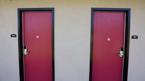 Two red doors with black frames, each marked with a number (106 and 107) on the wall. - Budget Inn (Lawndale)