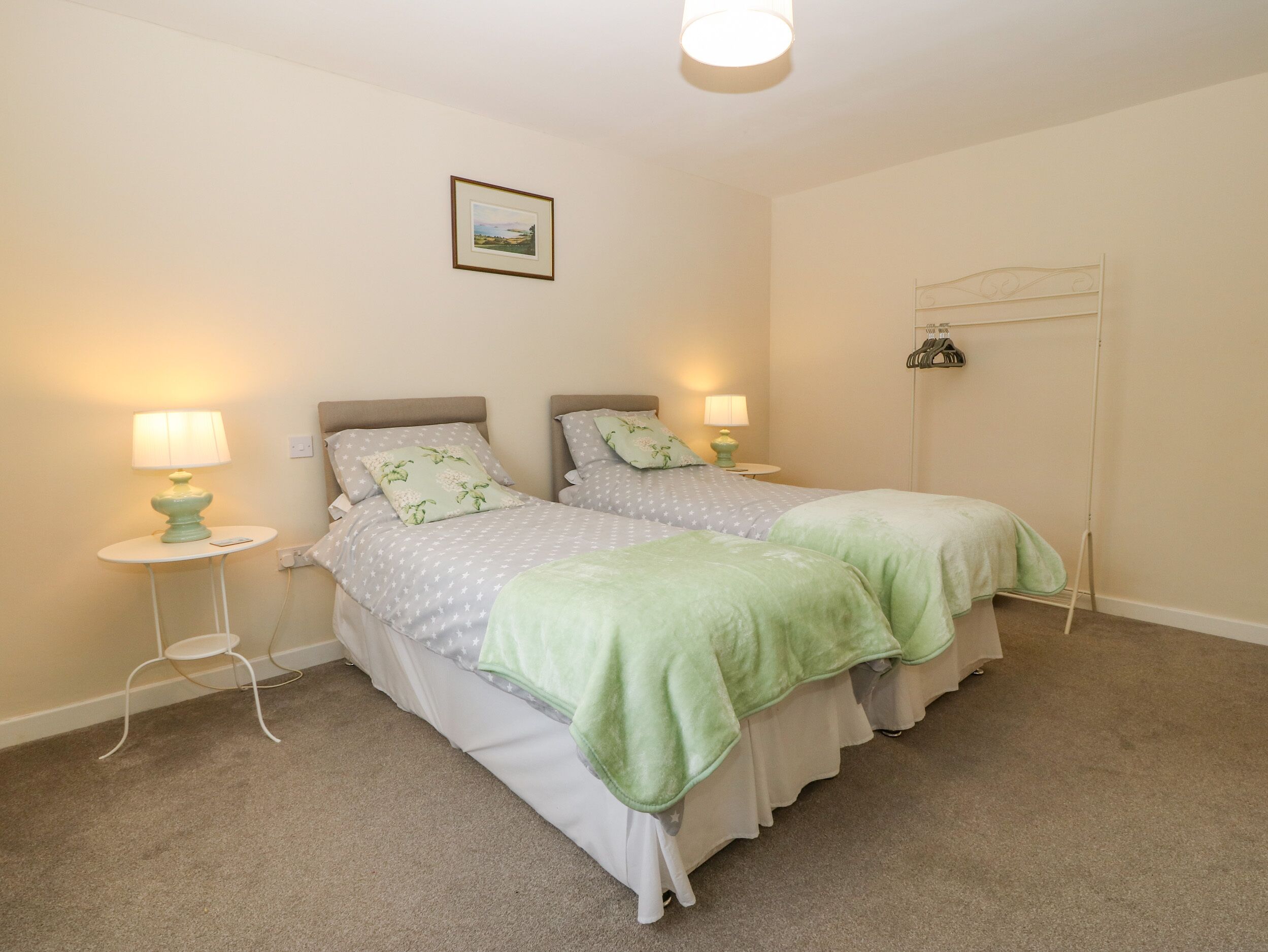 A bedroom with two beds, each with a nightstand, a lamp, and a framed picture on the wall.
