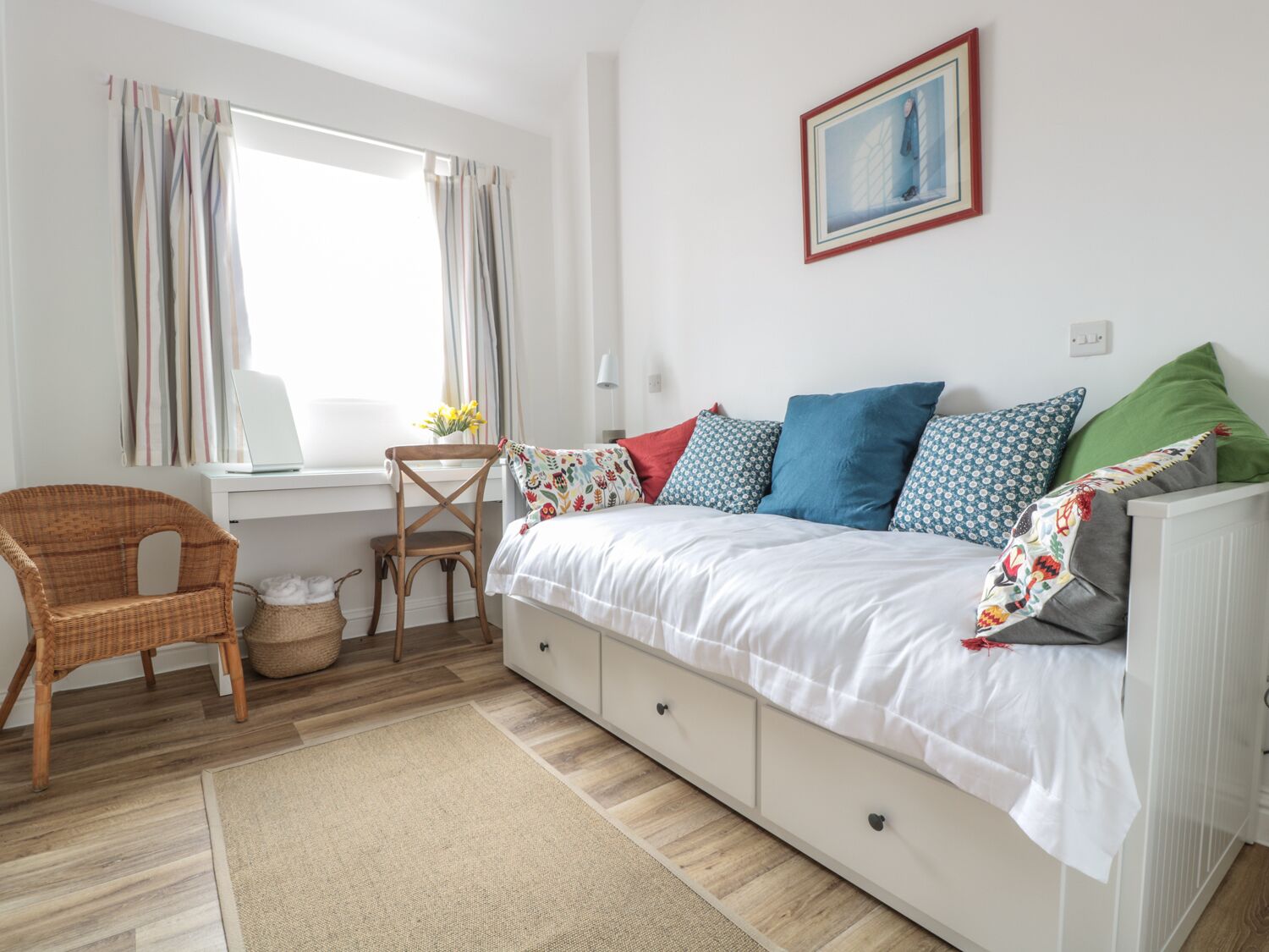 A bedroom with a bed, a desk, a chair, and a window with curtains.