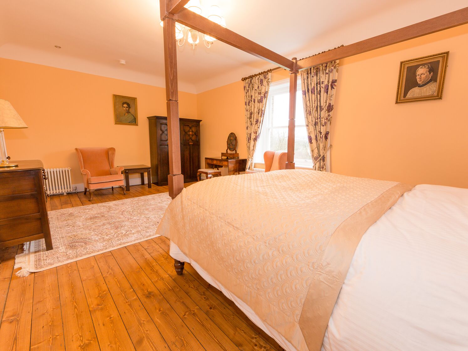 Un dormitorio con cama con dosel, suelo de madera y radiador.