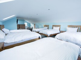 Habitación de hotel con cuatro camas individuales, un armario de madera, un escritorio y una lámpara en el techo.