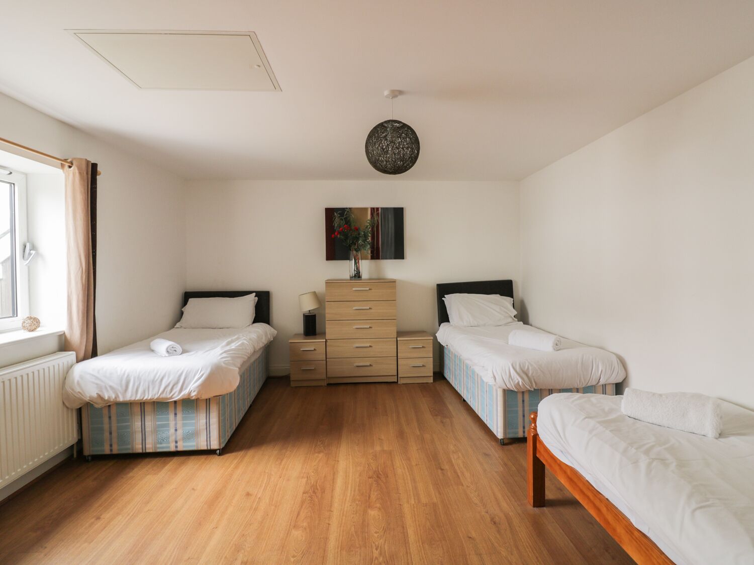A bedroom with two single beds, a dresser, a mirror, and a ceiling light fixture.