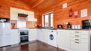 Eine kompakte Küche mit weißen Schränken, einer Mikrowelle, einem Backofen, einem Geschirrspüler und einer Waschmaschine.