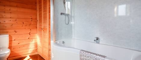 A bathroom with a wooden interior, a white bathtub, and a toilet.