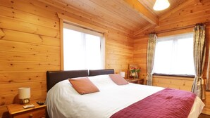 Ein Schlafzimmer einer Holzhütte mit einem Bett, Nachttischen und einer Kommode.