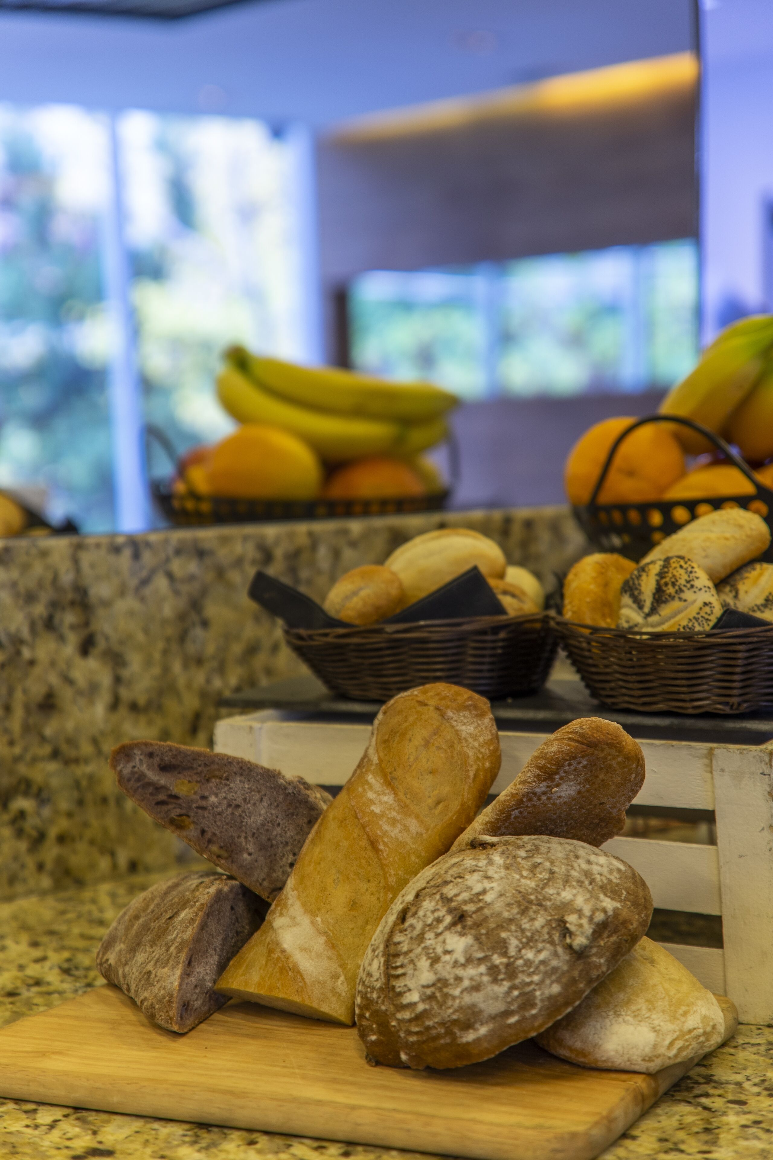 A variety of breads and fruits on a kitchen counter.