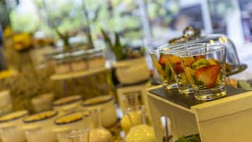 Ein Buffet mit verschiedenen Speisen und Getränken, darunter Obstbecher und Glaskästen.
