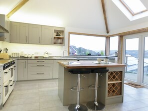 Una cocina moderna con una isla central, taburetes de bar y un amplio ventanal con vistas al paisaje.