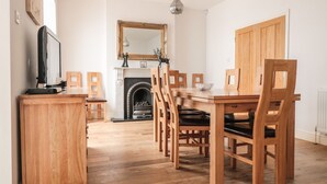 A dining area with a wooden table and chairs, a fireplace, and a mirror on the wall. - 33 Crescent Gardens (Bath)