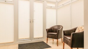 A room with a large sliding glass door, two leather chairs, and a doormat. - 33 Crescent Gardens (Bath)