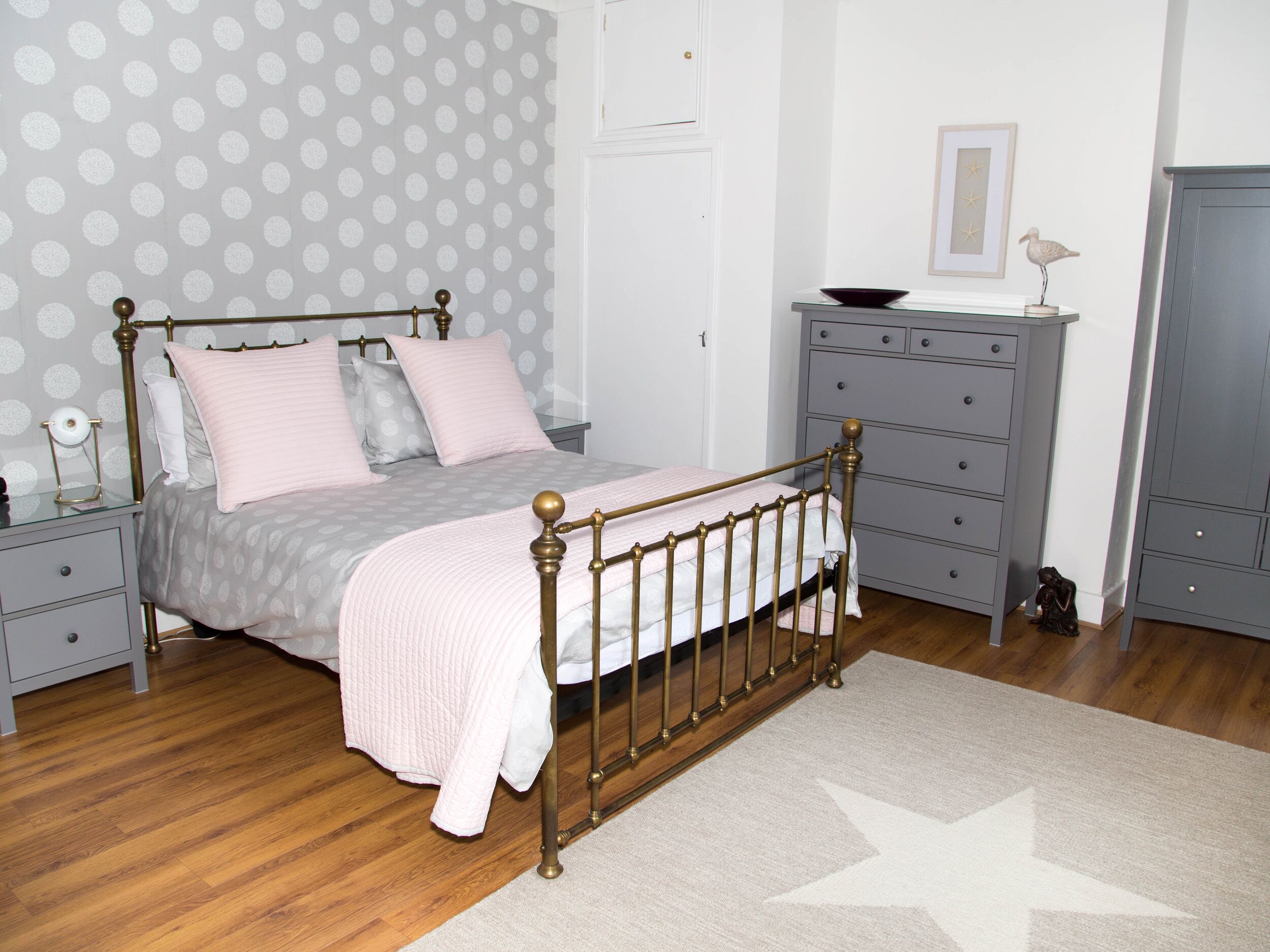 A neatly arranged bedroom with a bed, dresser, nightstand, and a star-patterned wall.