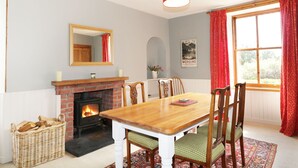 A dining room with a brick fireplace, wooden table, and chairs. - Annfield (Aberlour)