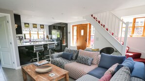 A modern living room with a sofa set, a wooden coffee table, and a staircase.