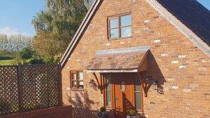 A brick house with a wooden door, a small window, and a porch with a roof.