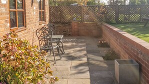 A patio with stone flooring, a brick wall, and a wooden fence.