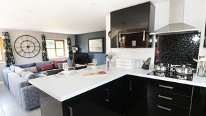 A modern kitchen with black cabinets, a white countertop, and a built-in stove.