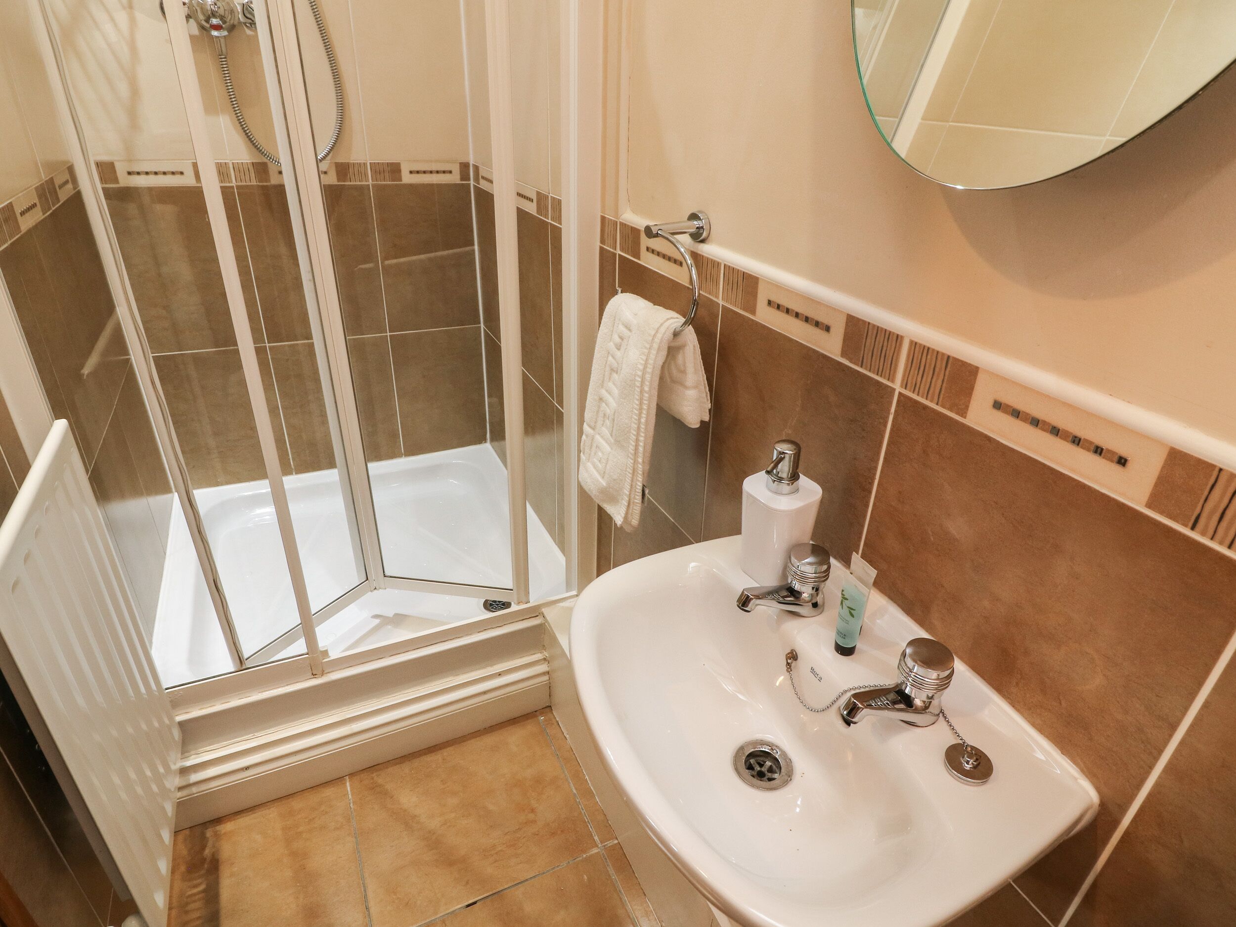 A bathroom with a glass-enclosed shower, a sink with a mirror, and a towel rack.