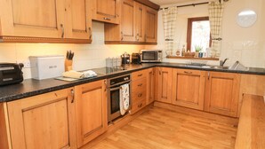 A kitchen with wooden cabinets, a microwave, a toaster, and a sink. - Clove Cottage (Appleby-in-Westmorland)