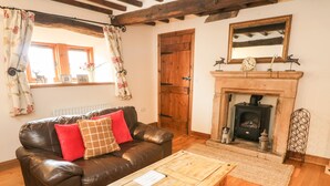 A cozy living room with a leather sofa, wooden coffee table, and a fireplace. - Clove Cottage (Appleby-in-Westmorland)
