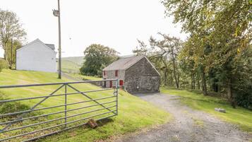 A rural landscape with a stone barn, a white building, and a metal gate.