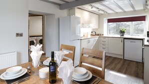 A modern kitchen with white cabinets, a built-in oven, and a window with a view of trees. - Bryndan (Machynlleth)