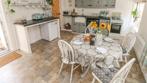 Une cuisine compacte avec un coin repas, comprenant un petit réfrigérateur, un four à micro-ondes et une cuisinière.