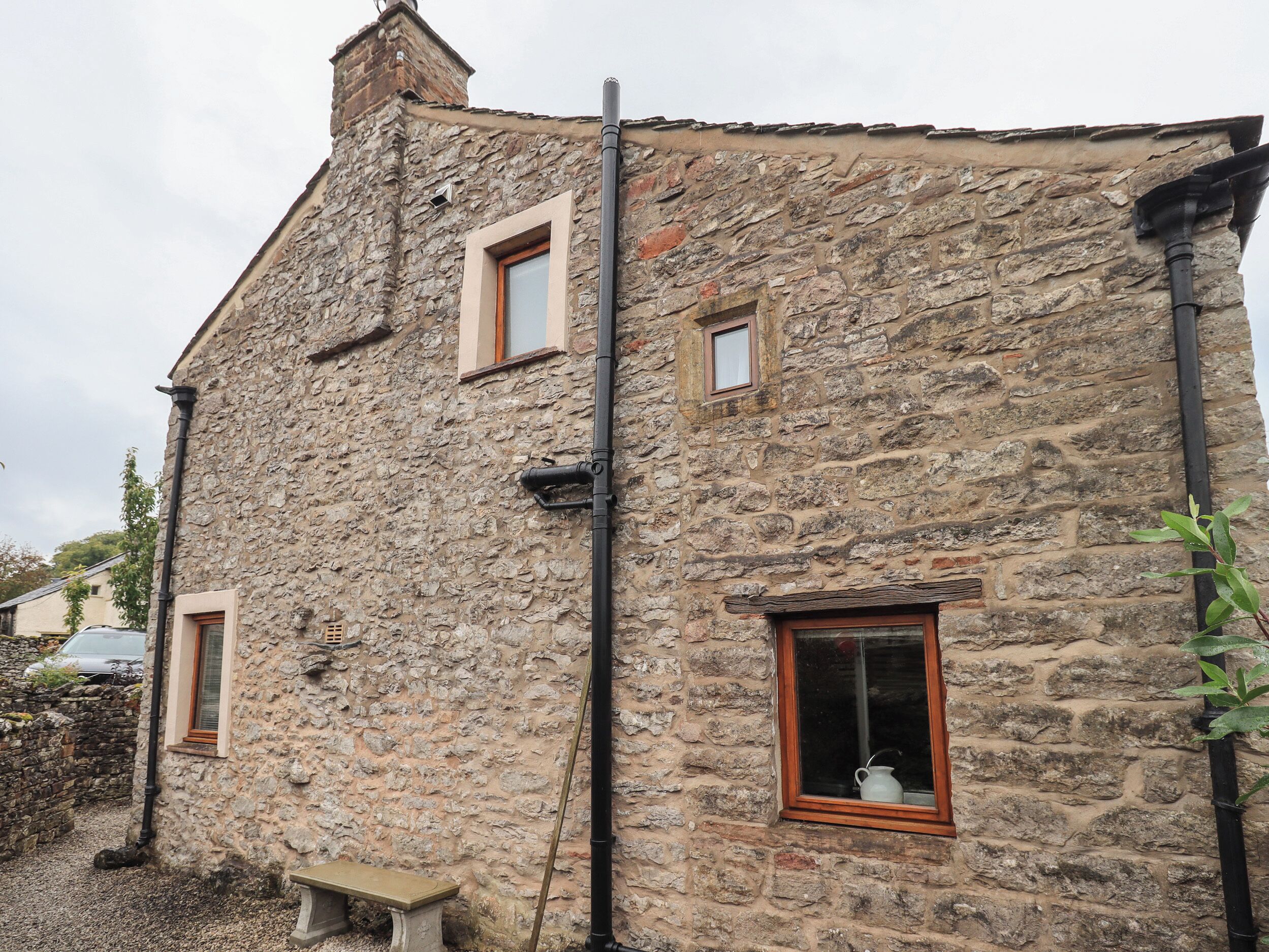 A stone building with two windows and a bench outside.