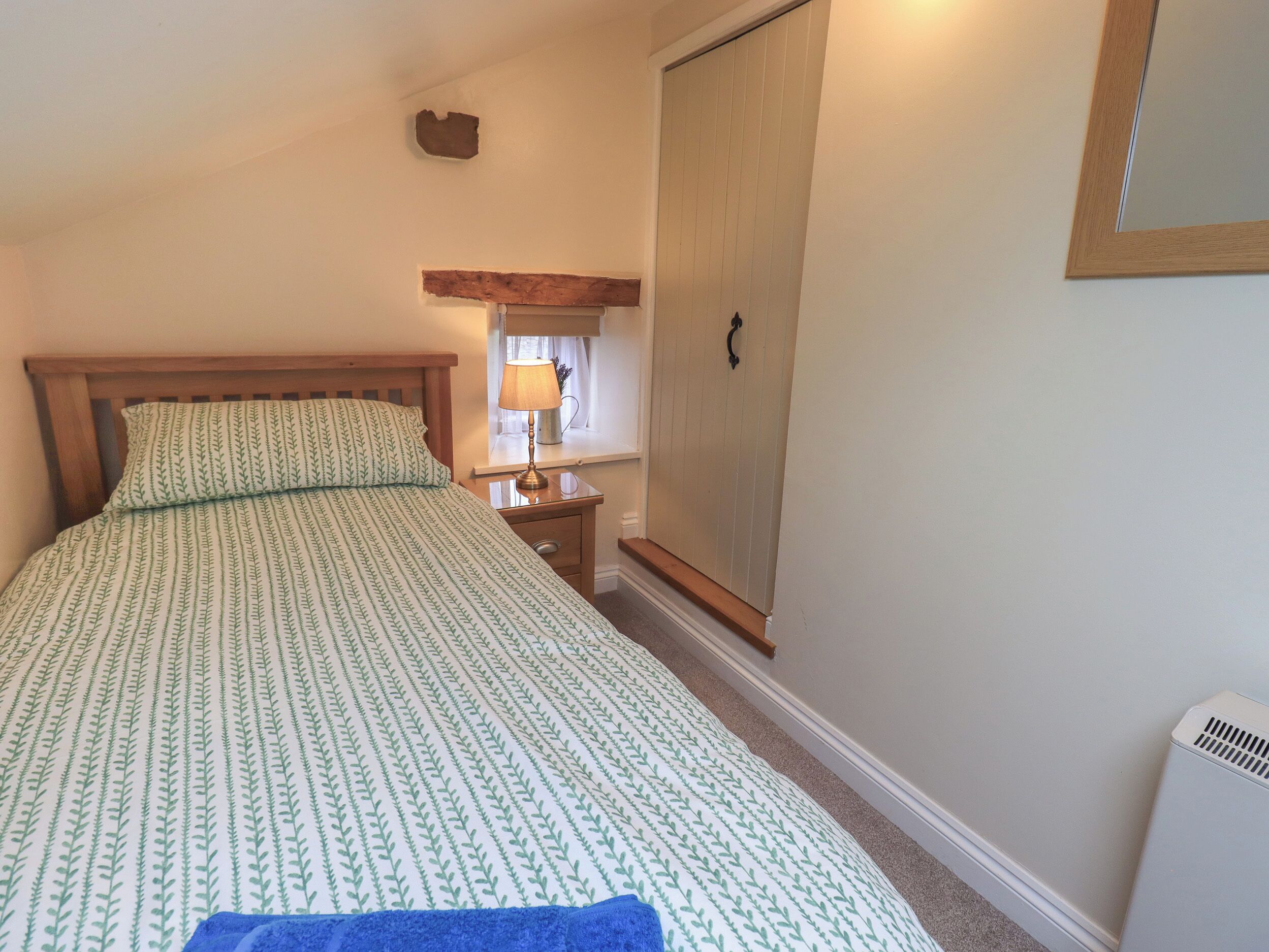 Quarto com cama, mesa de cabeceira, abajur, guarda-roupa e radiador.