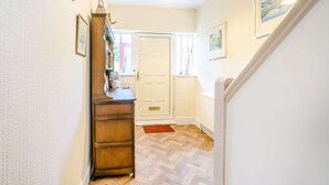 A hallway with a wooden dresser, a white door, and a red doormat. - The Perks (Scarborough)