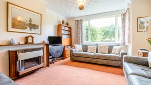 A living room with a fireplace, sofa, and a television. - The Perks (Scarborough)