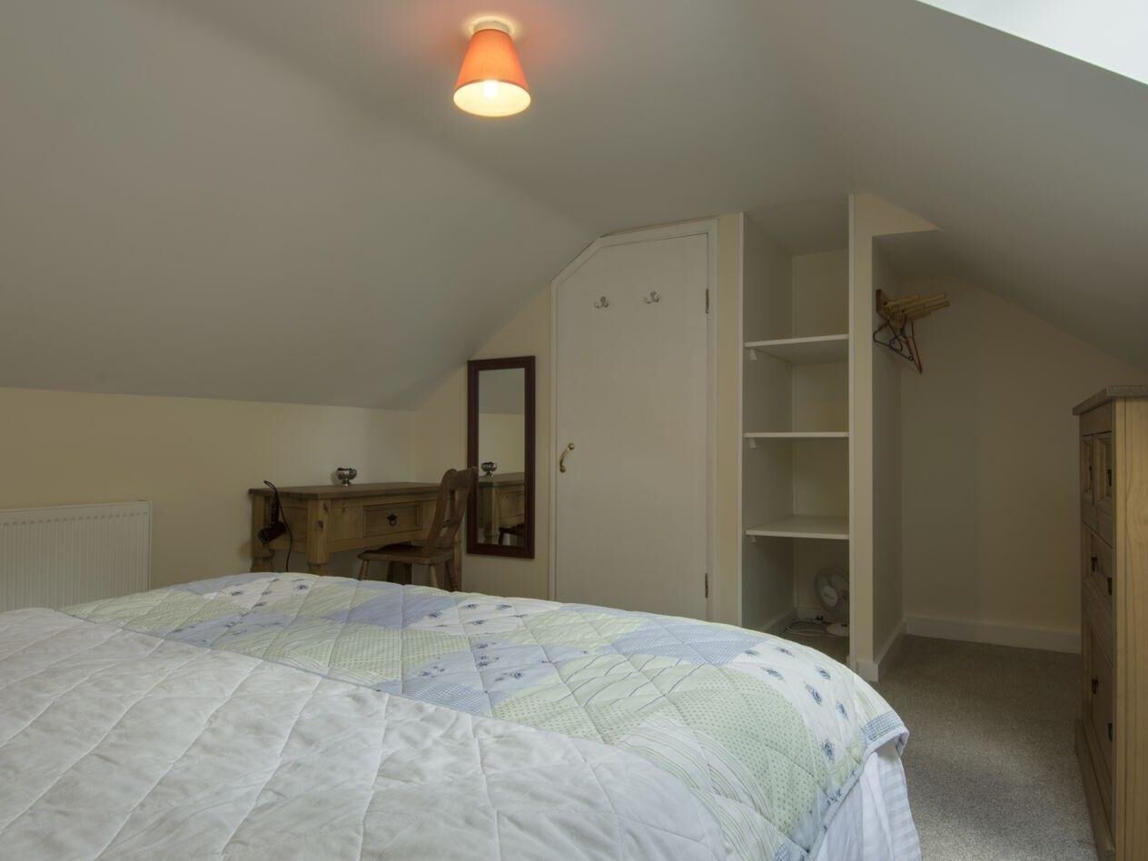Une chambre à coucher comprenant un lit, un bureau, une chaise, une armoire et un radiateur.
