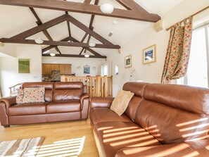 A spacious living room with two brown leather sofas, wooden flooring, and a high ceiling with exposed beams. - Skiddaw (Cockermouth)