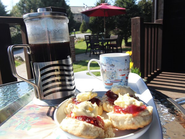 Une table avec une carafe de boisson, une tasse et une assiette de scones accompagnés de confiture.