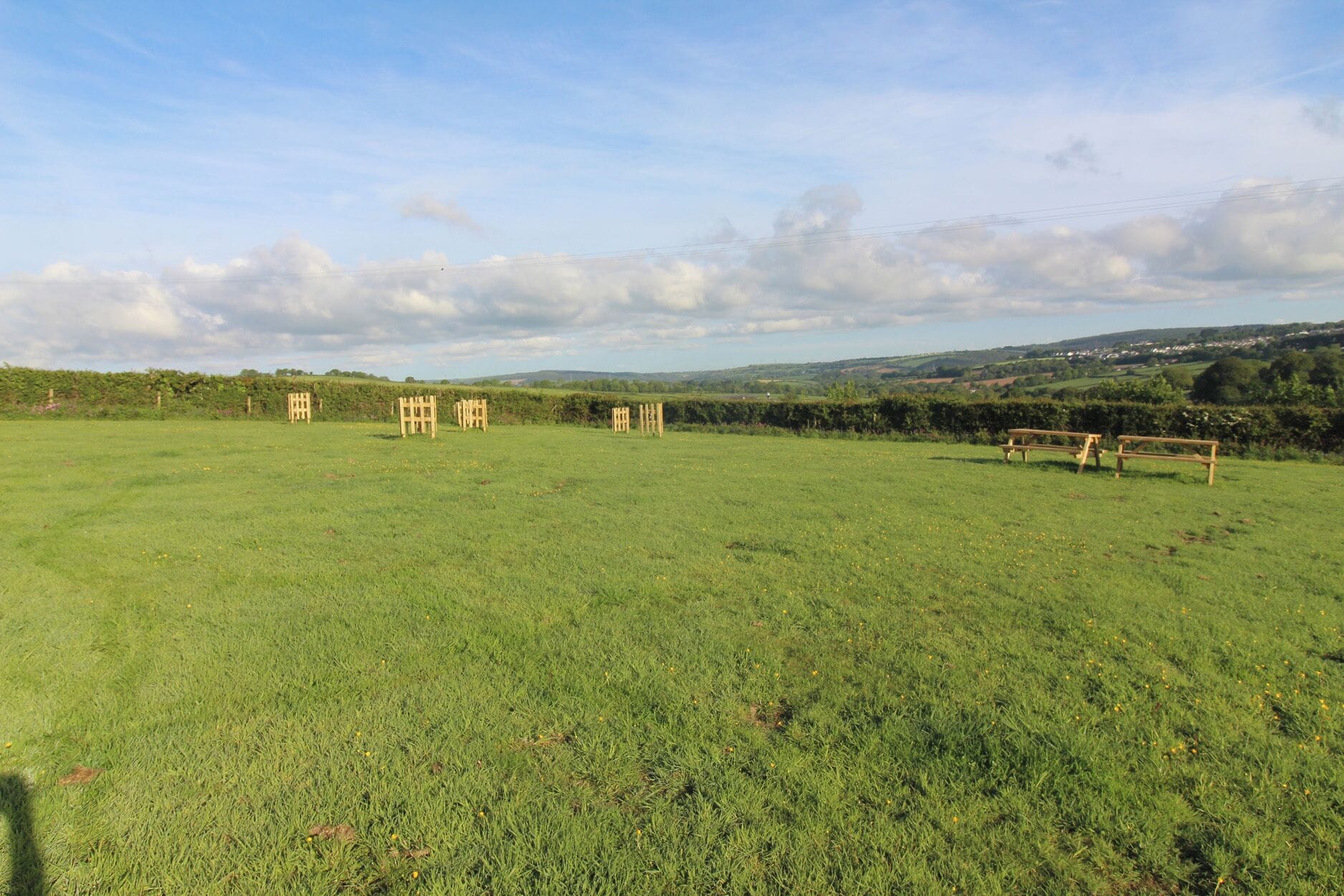 Un campo cubierto de césped con mesas de picnic y una valla.