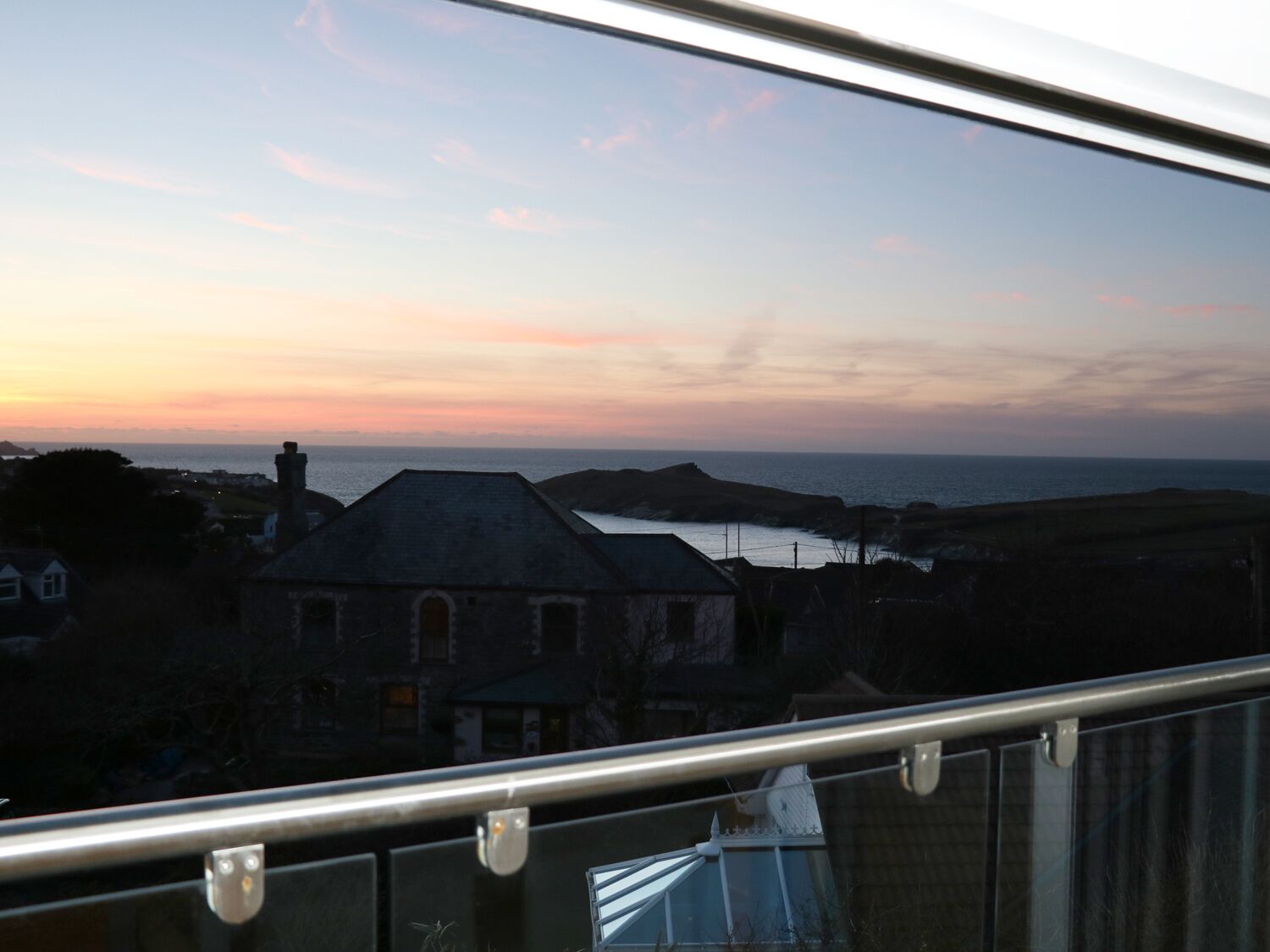 Uma cidade costeira ao pôr do sol, com edifícios e vista para o mar.